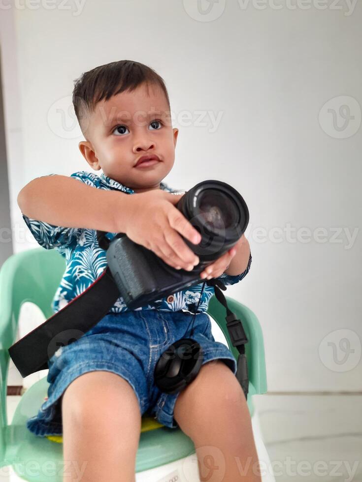 a toddler boy holding a DSLR camera photo
