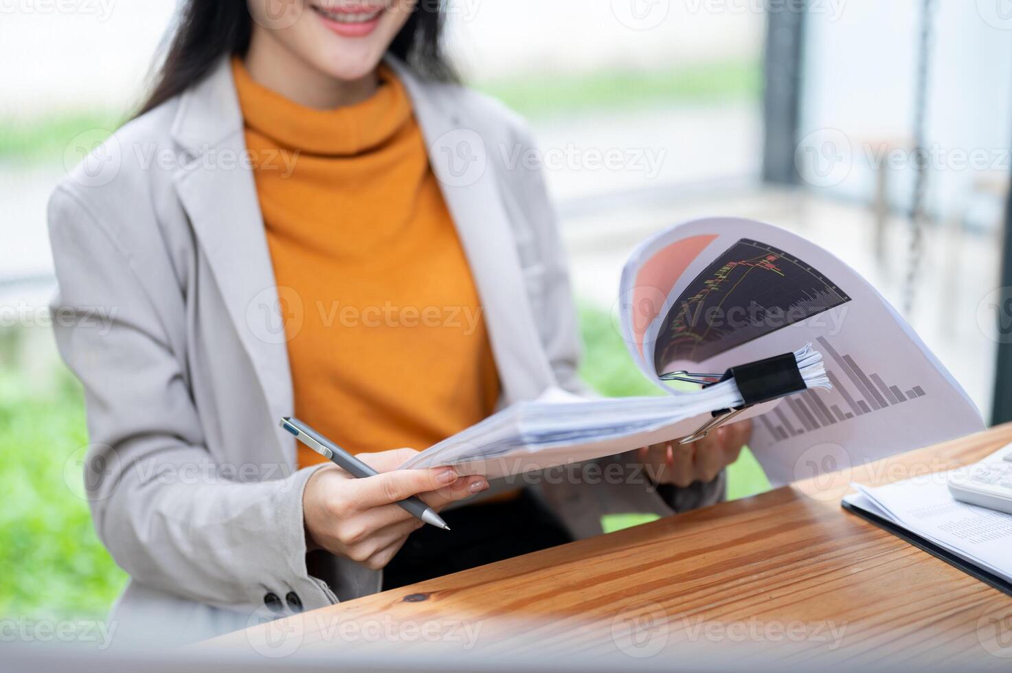 A cropped image of a businesswoman is reading and reviewing business financial reports at her desk. photo