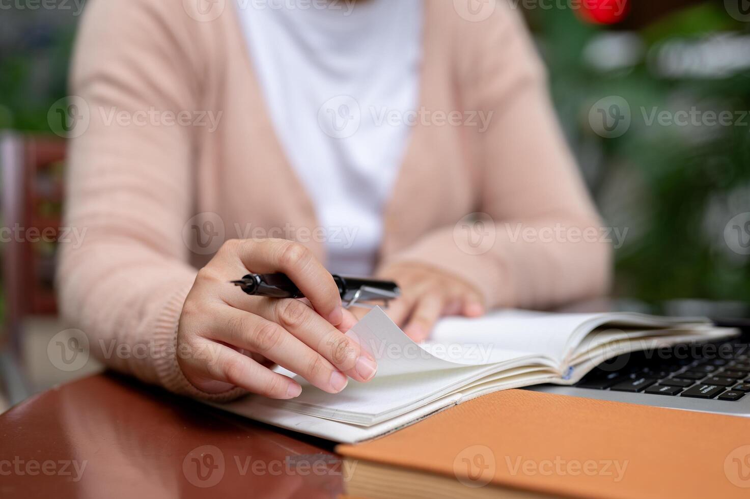 A woman in casual clothes holding a pen, writing something in a 