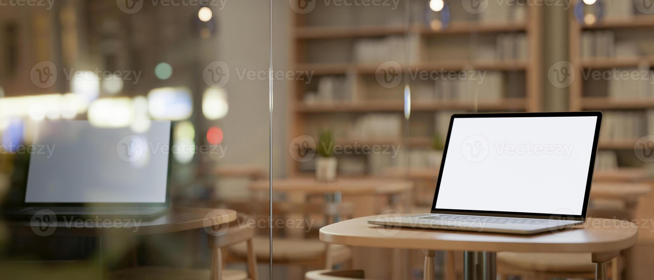 A laptop computer mockup on a wooden table by the window in a contemporary coffee shop or library. photo