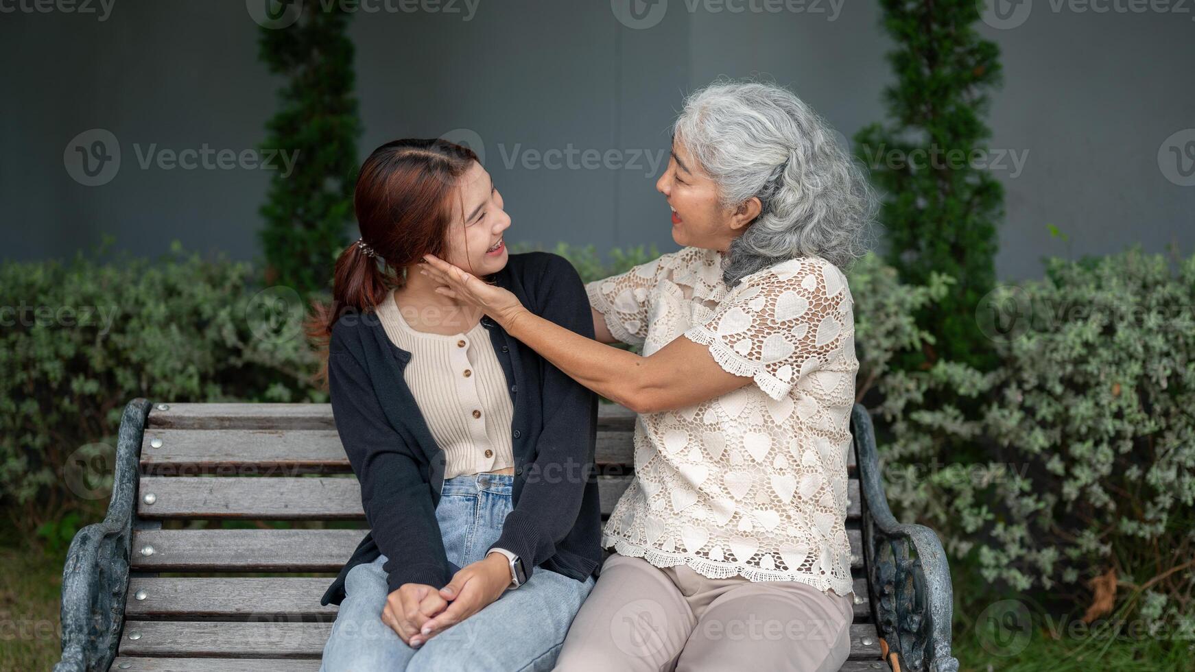 A happy retired Asian grandma is enjoying talking with her granddaughter in a garden. photo