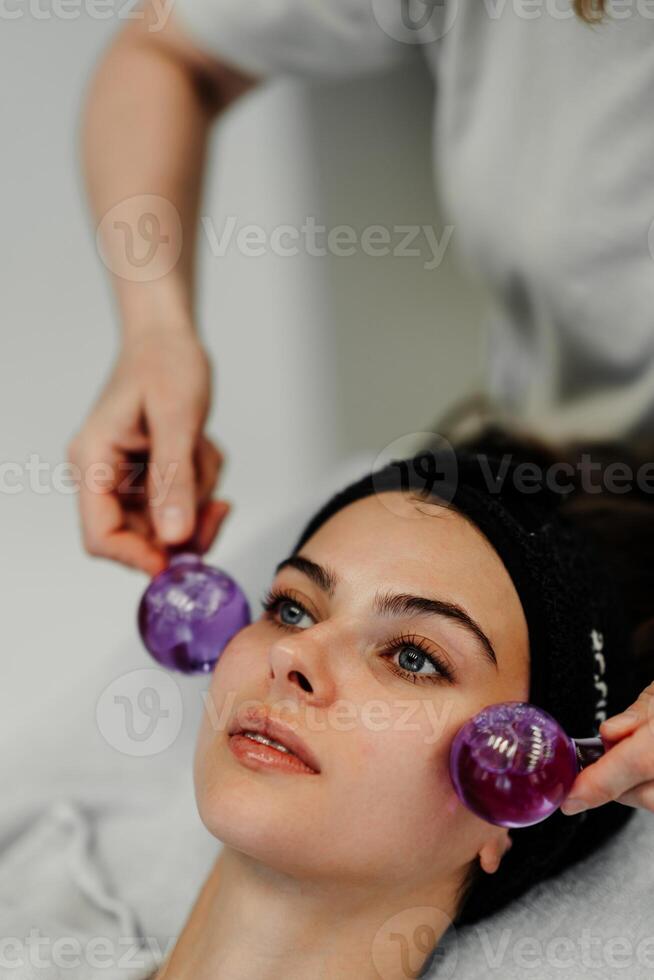 The master gives the client a relaxing facial massage using cold cryo spheres. photo