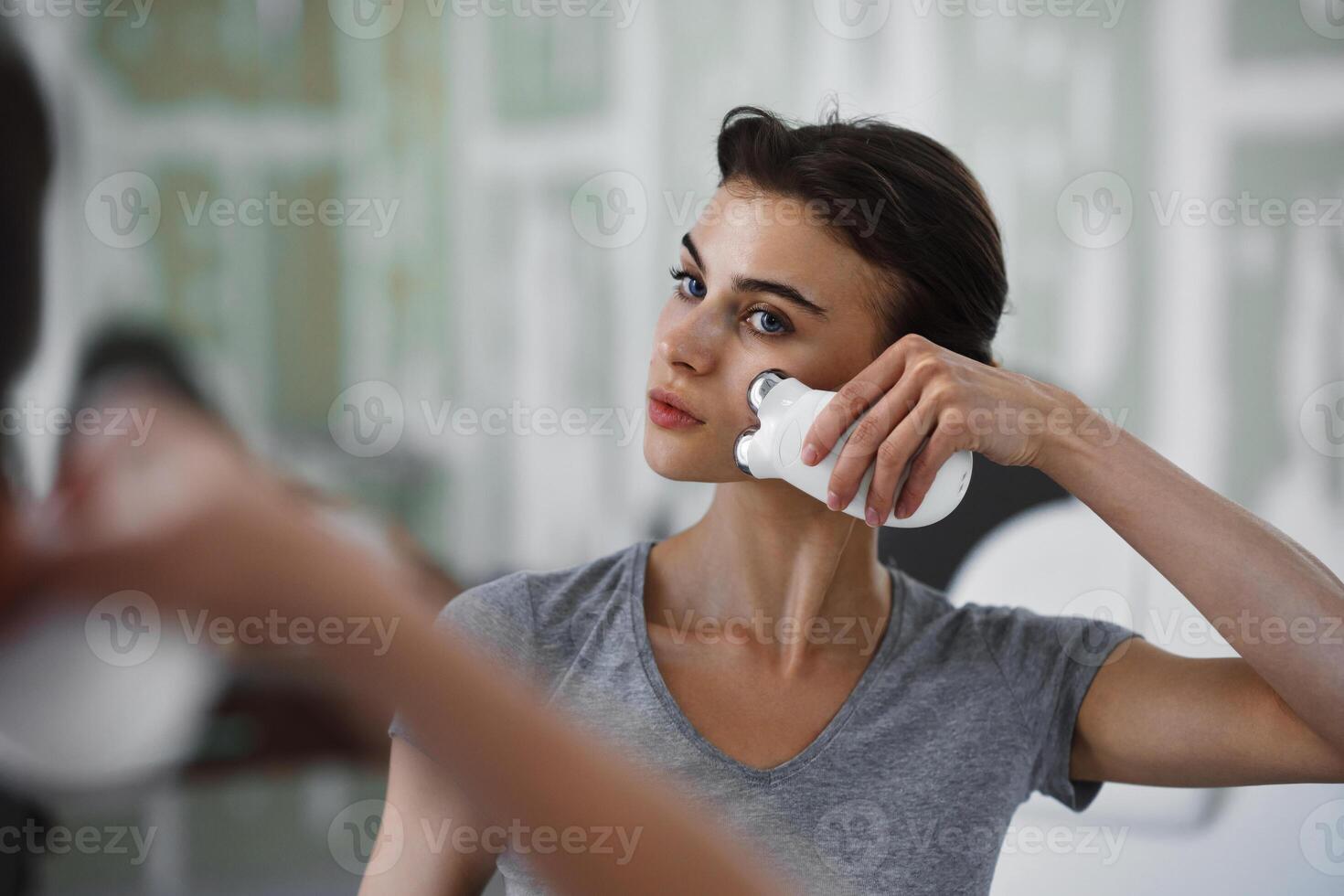 Facial skin care. A woman is doing a face massage using a massager that passes micro current. photo
