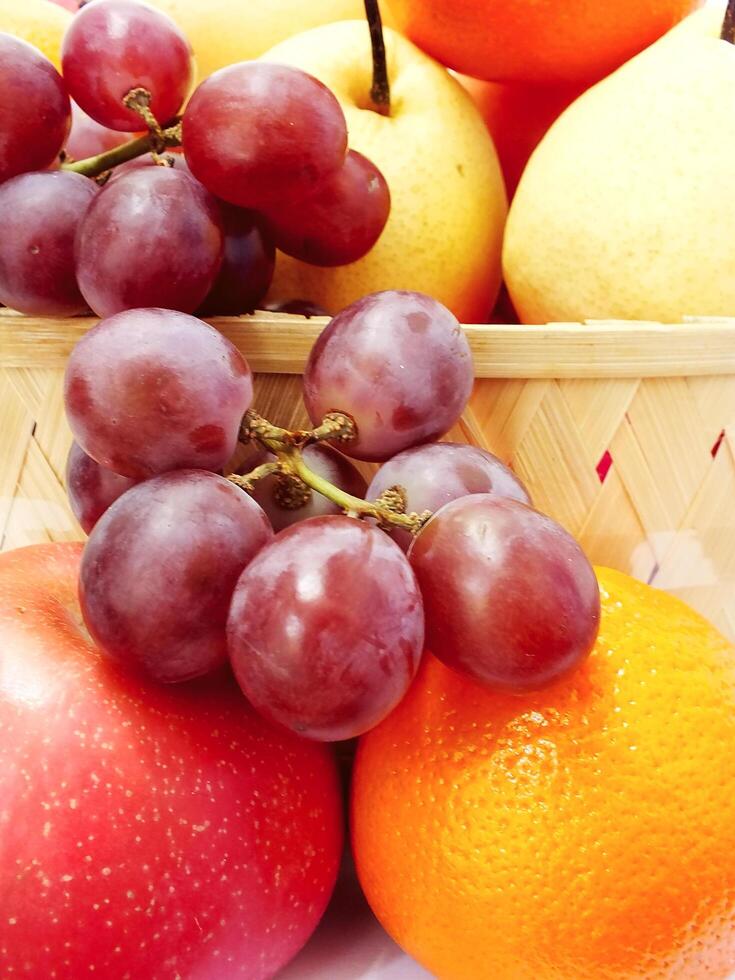 mix fruit on wooden basket grape apple pear orange. Harvesting from fruit garden into fruit store photo