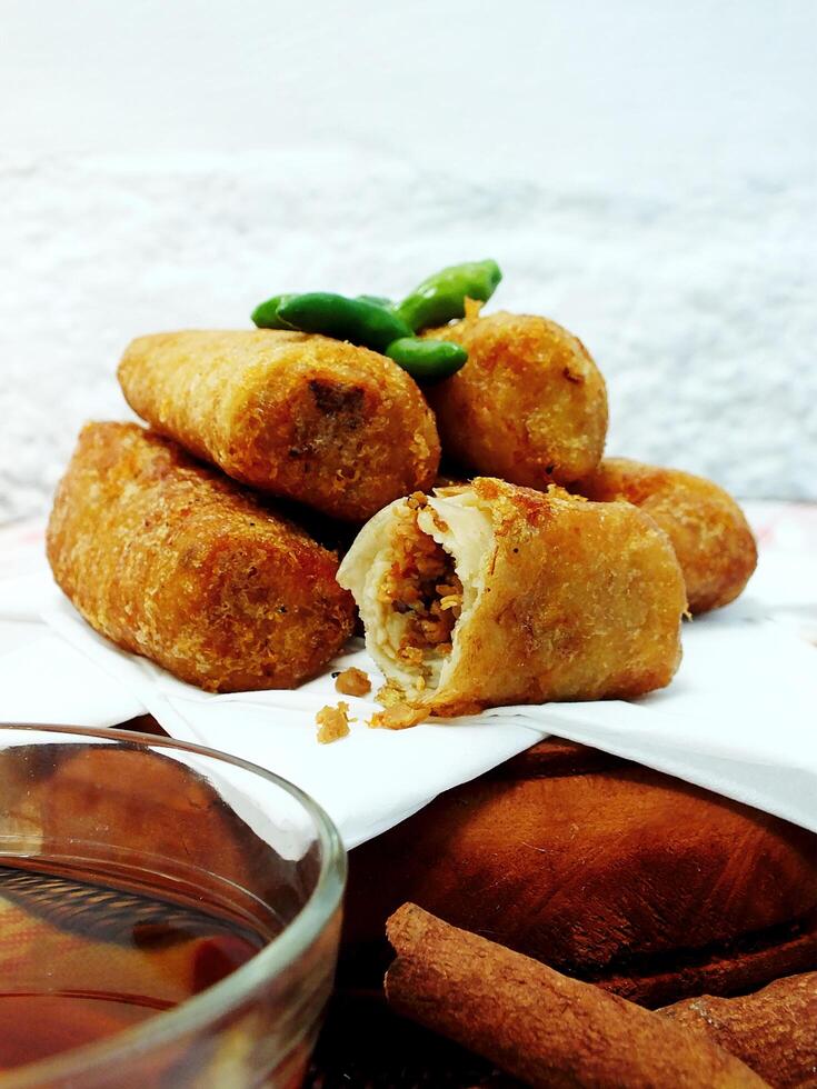 Traditional Indonesian snack Sosis Solo from Central Java, made from savory flour dough and filled with delicious minced chicken or beef then fried. More delicious if eaten with green cayenne pepper photo