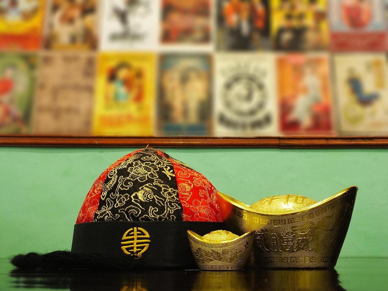 Chinese gold ingots and cheongsam hat on wooden table background. Chinese New Year concept image for good luck, wealth and prosperity. photo