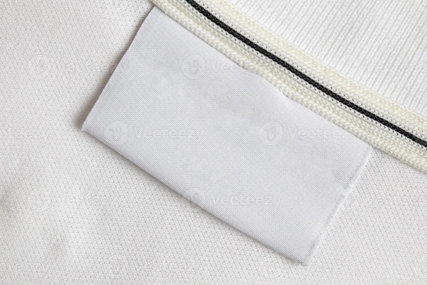 Blank white laundry care clothes label on white shirt fabric texture background photo