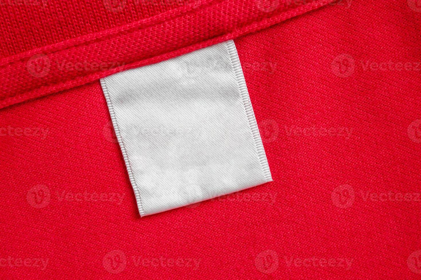 Blank white laundry care clothes label on red shirt fabric texture background photo