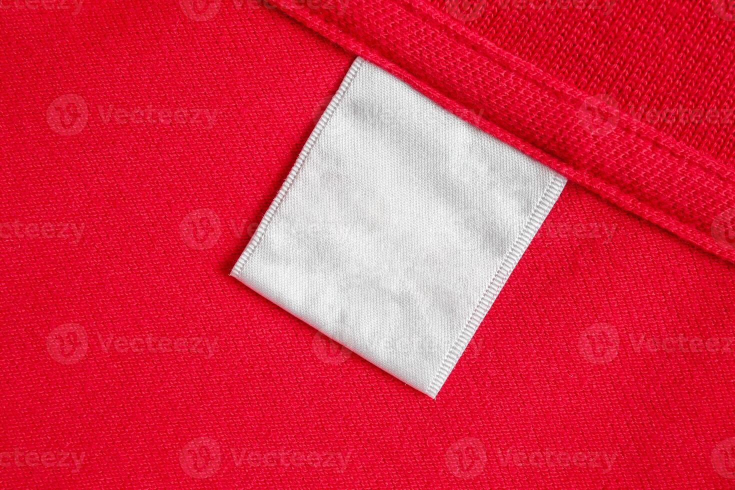 Blank white laundry care clothes label on red shirt fabric texture background photo