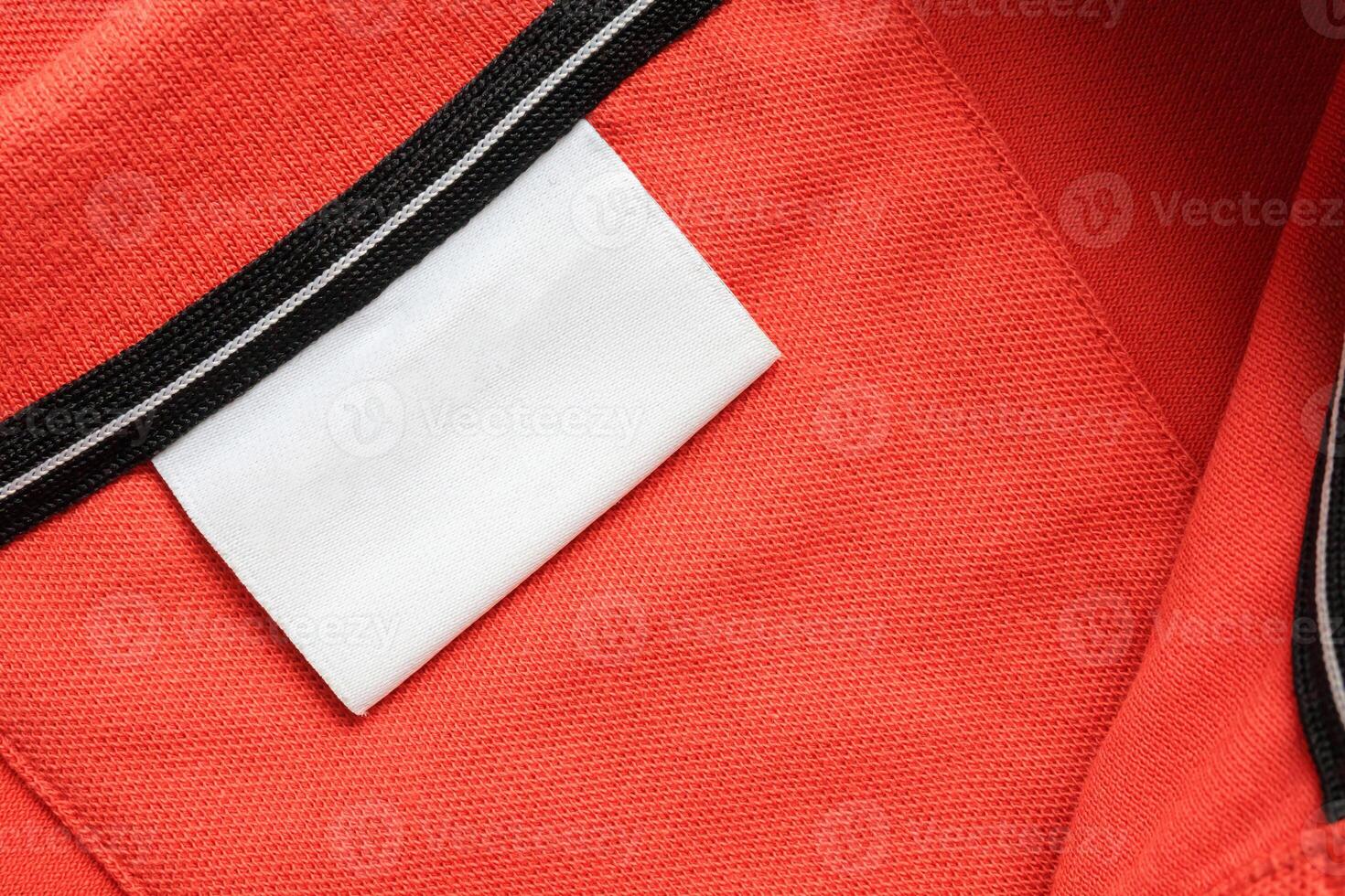 Blank white laundry care clothes label on orange shirt fabric texture background photo
