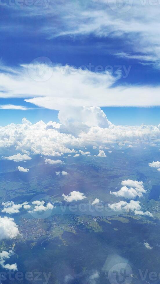 Vertical view of a blue sky with white fluffy cumulus clouds from an airplane window photo
