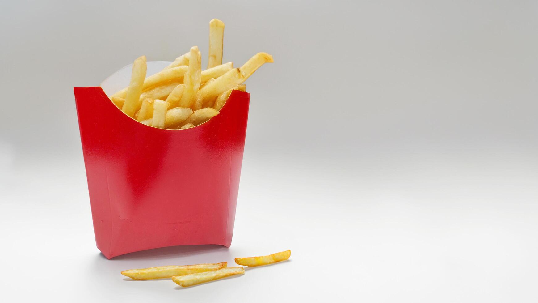 French fries in a red paper box isolated on a white background. Foreground. Fast food, fatty, high-calorie, unhealthy food photo