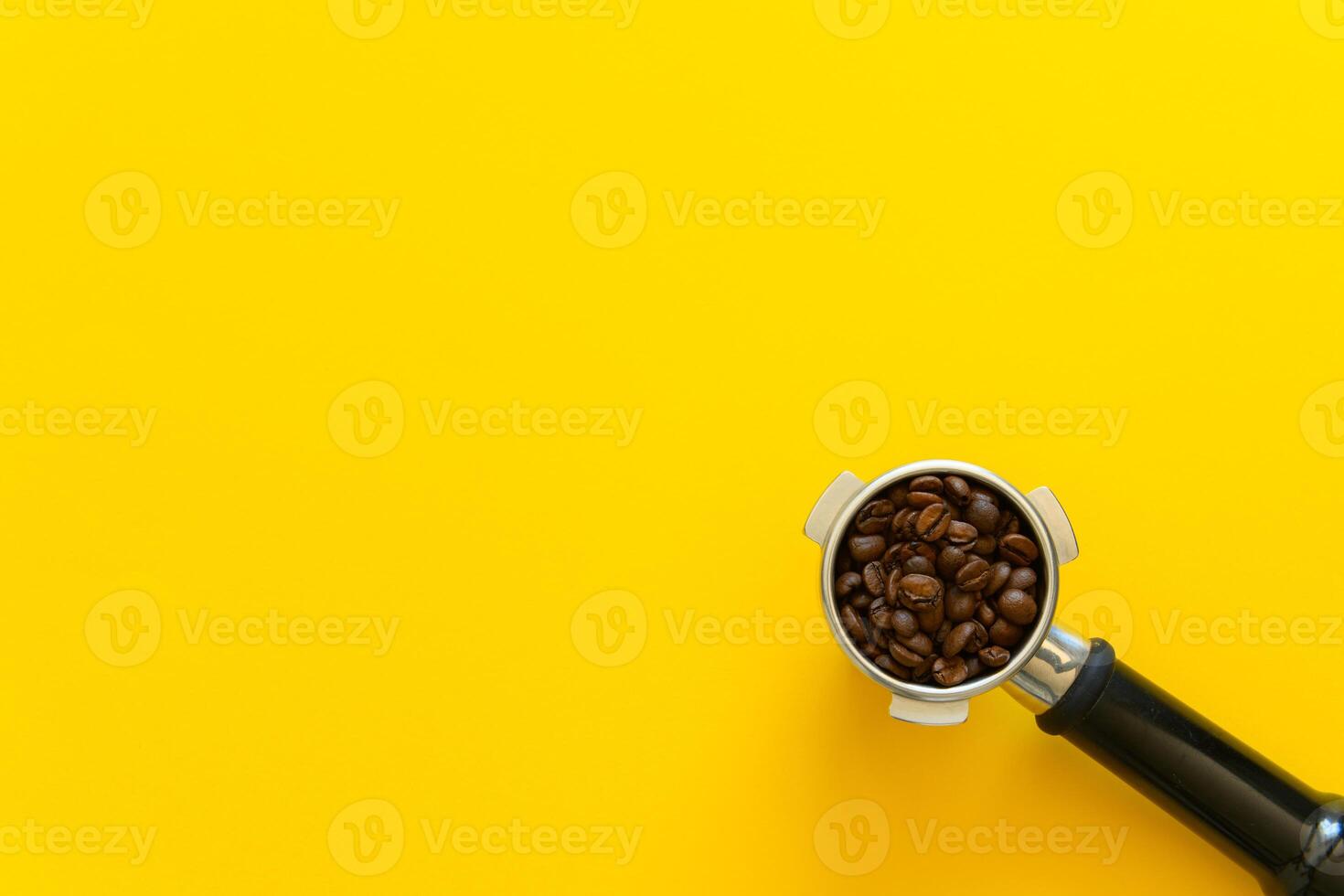 Espresso portafilter with whole coffee beans on a yellow background photo