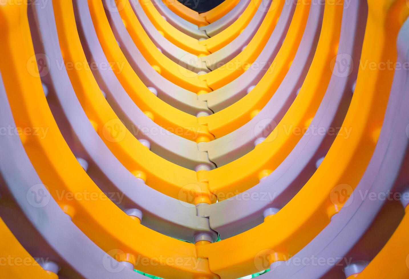 Yellow and White Plastic Children's Play Tunnel in Indoor Playground, Curved colorful plastic molding in abstract background. photo