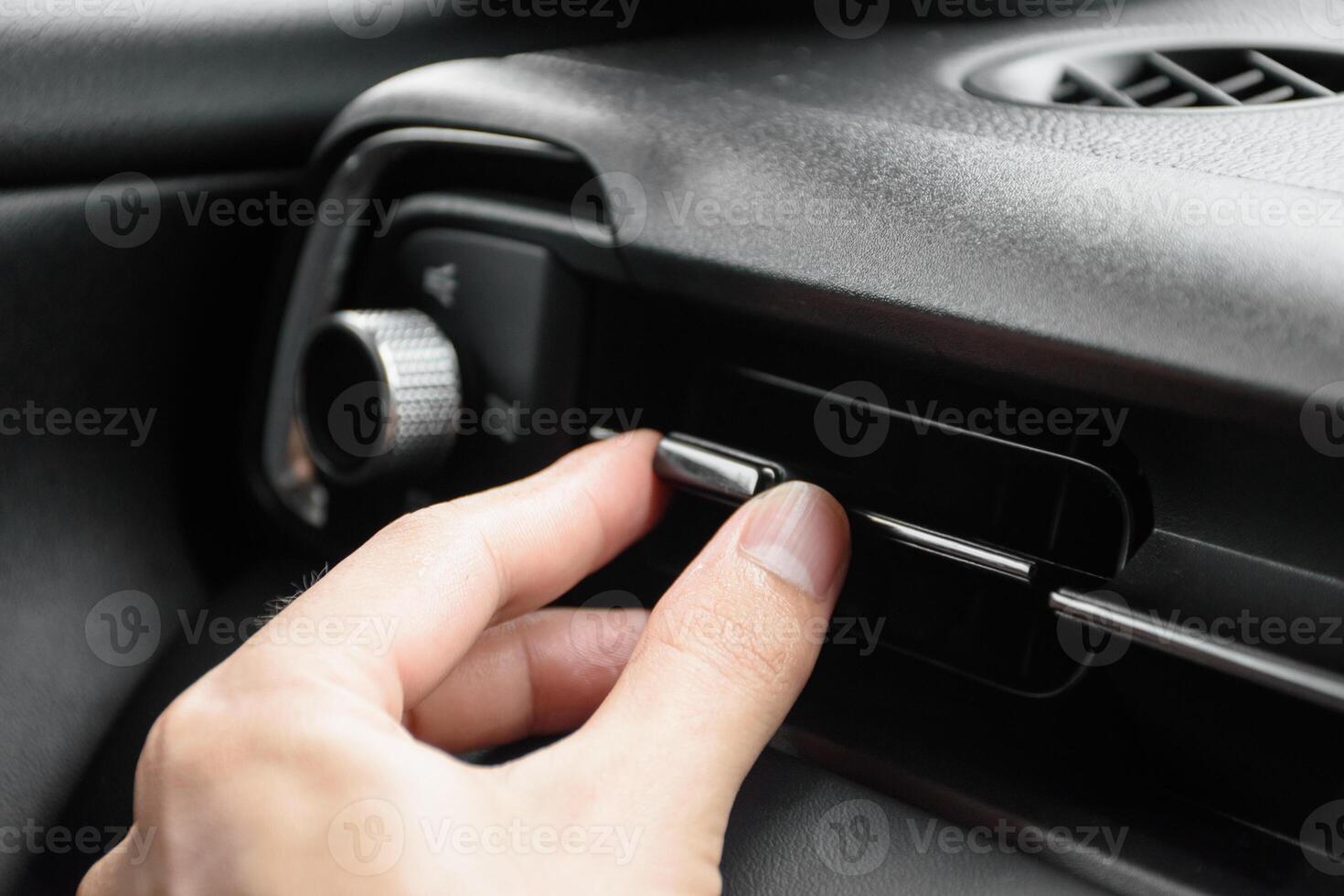 Close up the driver hand adjusts the wind direction of the air vent in the modern car, button direction adjustment of the air conditioning system in the car, Automotive air conditioning concept 2024. photo