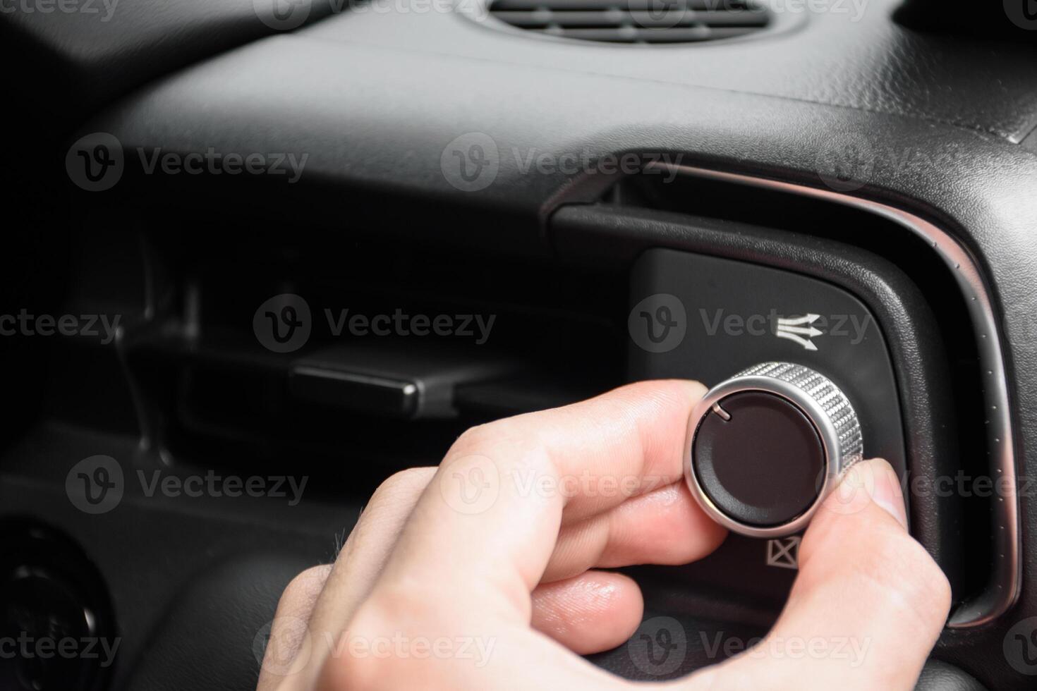 Hand turning the air conditioning control button inside the car for changing the air conditioning mode in a luxury and modern car in year 2024. photo