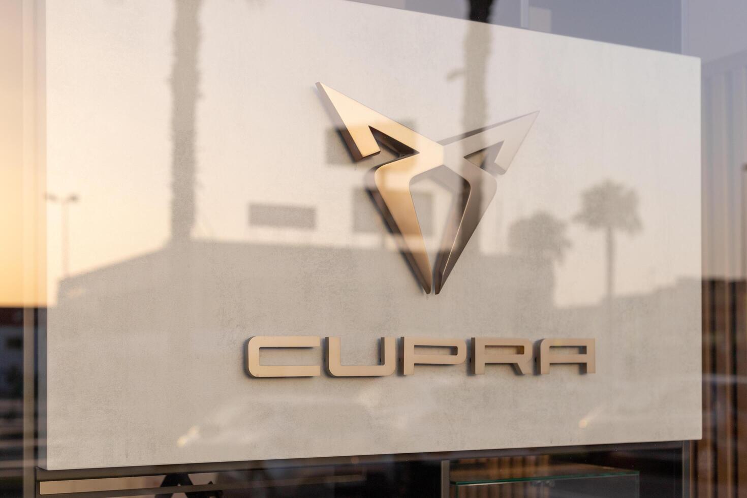 Torrevieja, Spain - 09-07-2024, Cupra logo, highlighted by golden hues of a setting sun. Ideal for automotive branding, marketing materials, and editorial content on modern car brands. photo