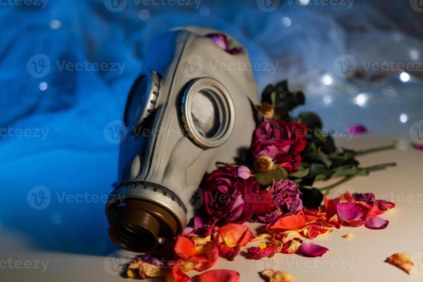 Gas mask among withered roses on table photo