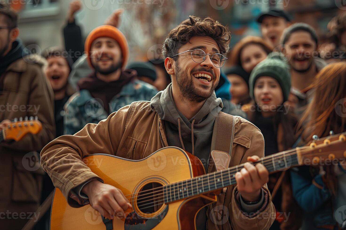 Photo of a man playing the guitar and singing, surrounded by a group of friends