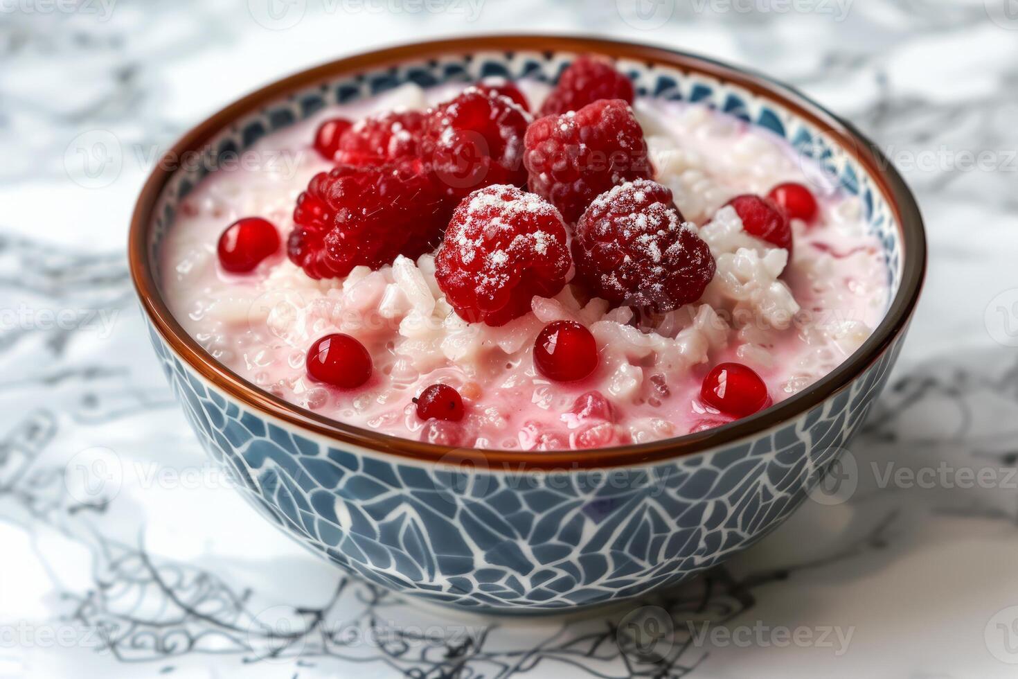 Bowl of rice pudding with fresh raspberries and redcurrants being sprinkled with powdered sugar photo