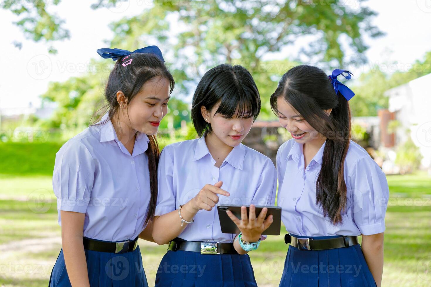 Group of Asian school girls teen friend in school uniform together look tablet happy smiling photo