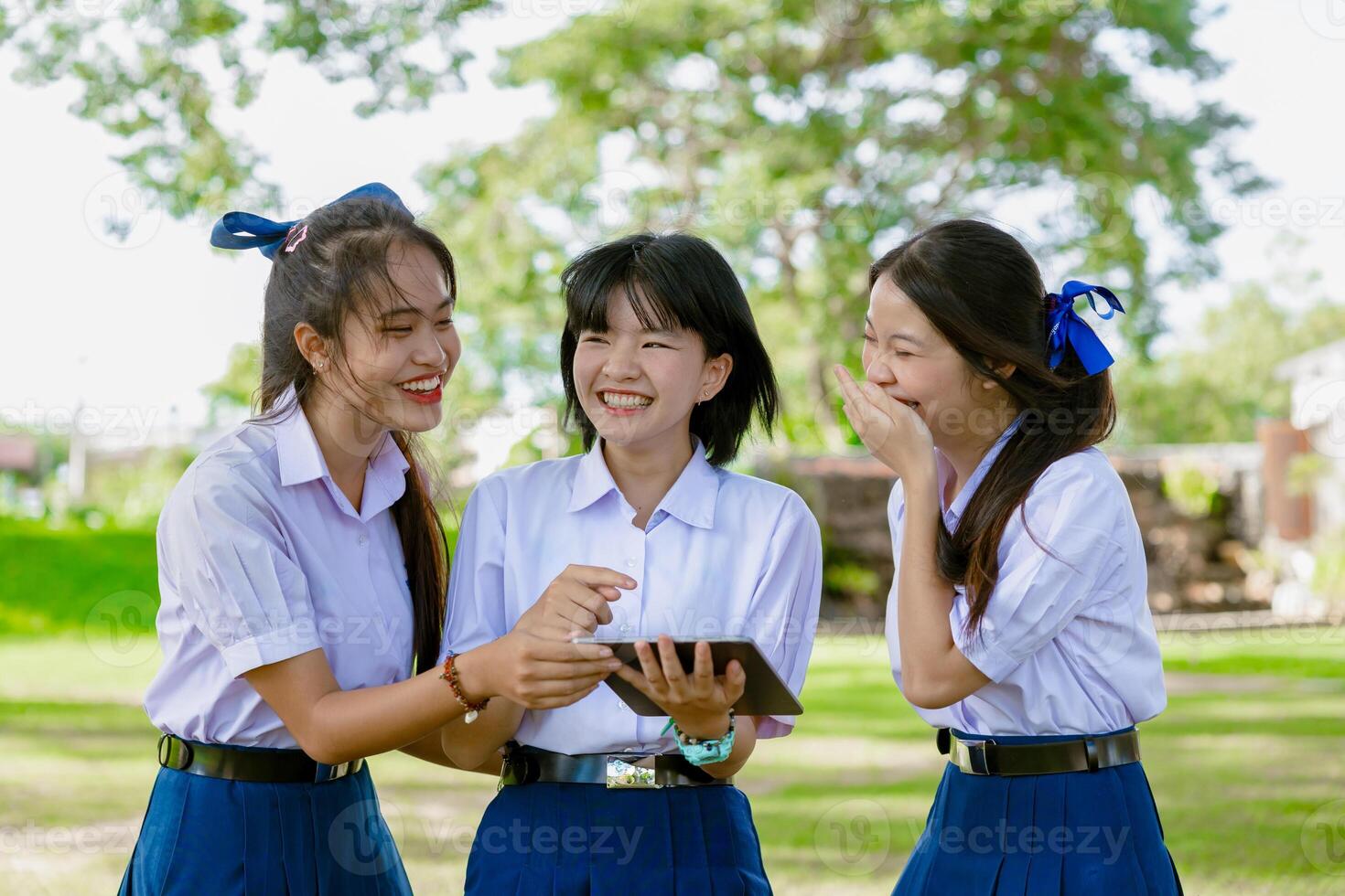 Group of Asian school girls teen friend in school uniform together look tablet happy smiling photo