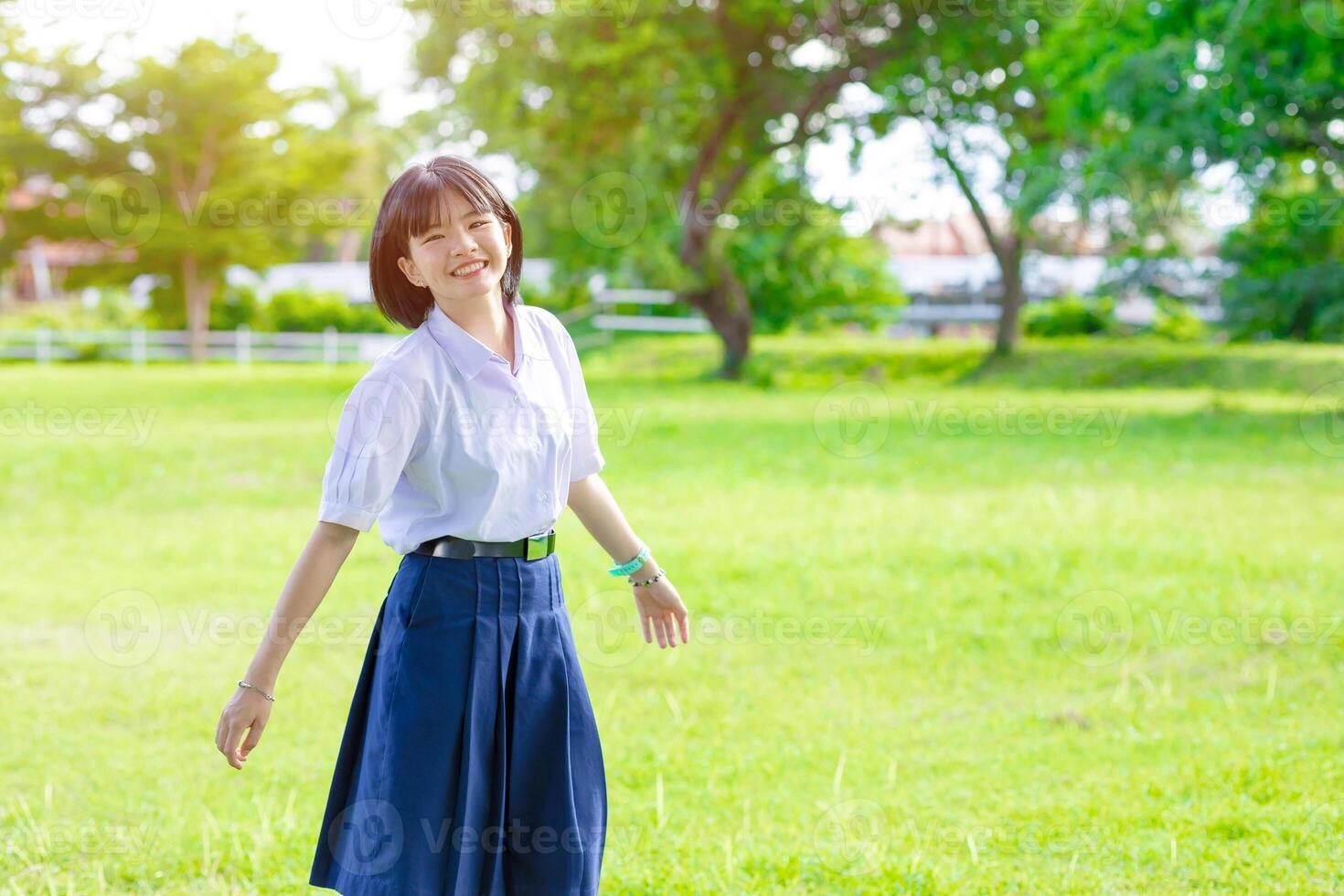 Portrait cute lovely happy Asian student school uniform girl in at green park outdoor photo