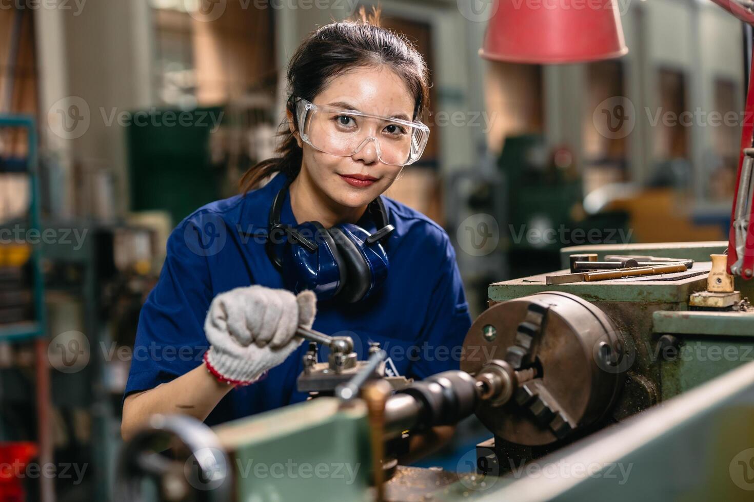 Portrait happy engineer worker with safety eyes protection glasses professional working with metal lathe milling machine heavy industry factory. photo
