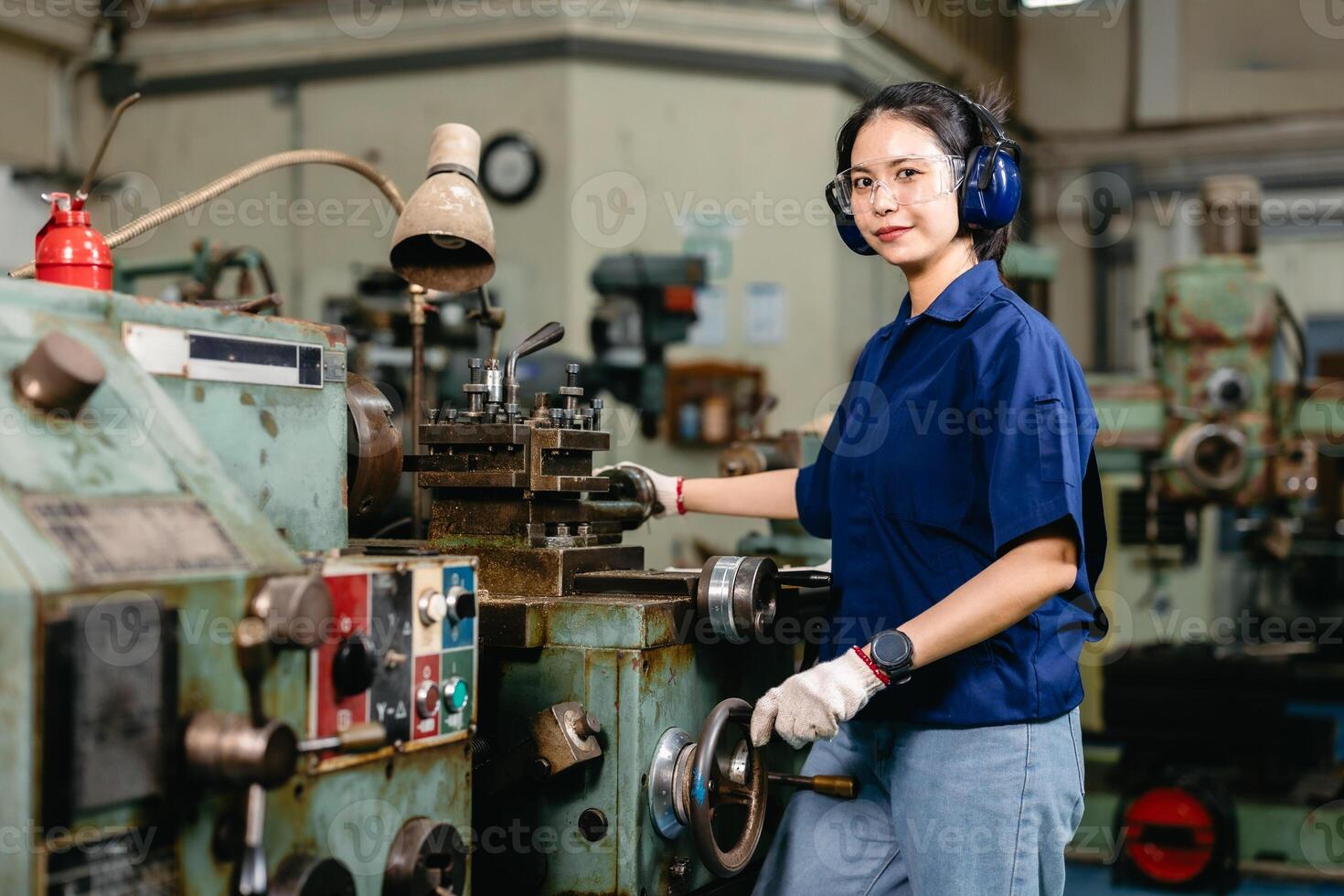 Portrait happy engineer worker with safety eyes protection glasses professional working with metal lathe milling machine heavy industry factory. photo