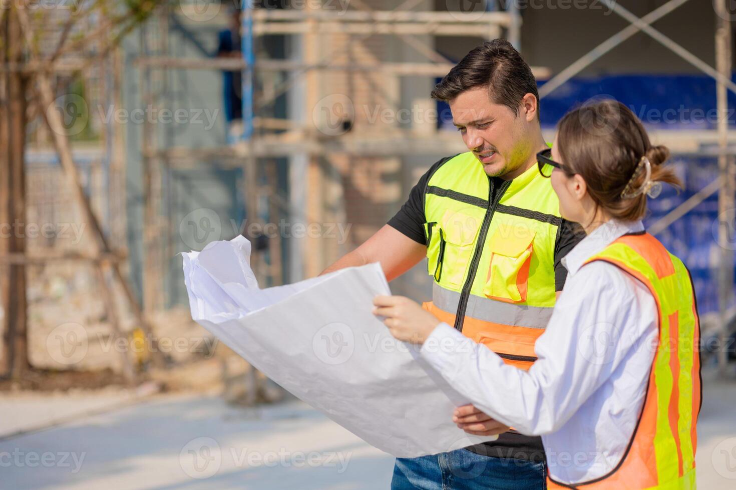 Construction Workers Discussing Blueprint at Building Site photo