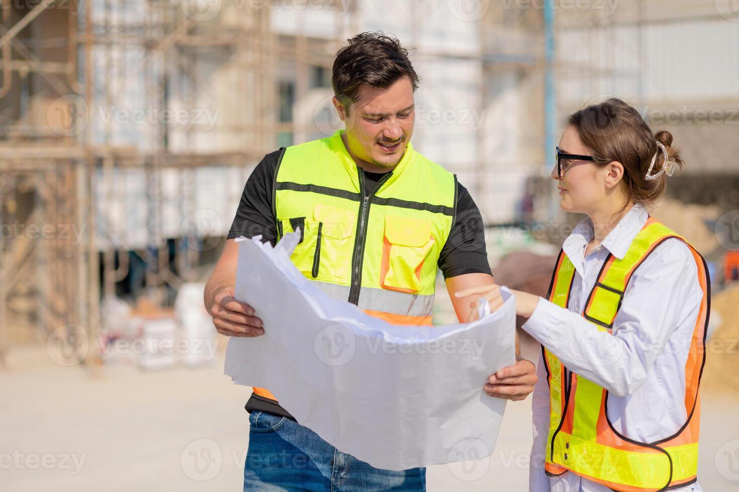 Construction Workers Discussing Blueprint at Building Site photo
