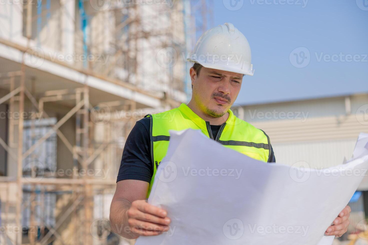 Construction Worker Reviewing Blueprints at Building Site photo