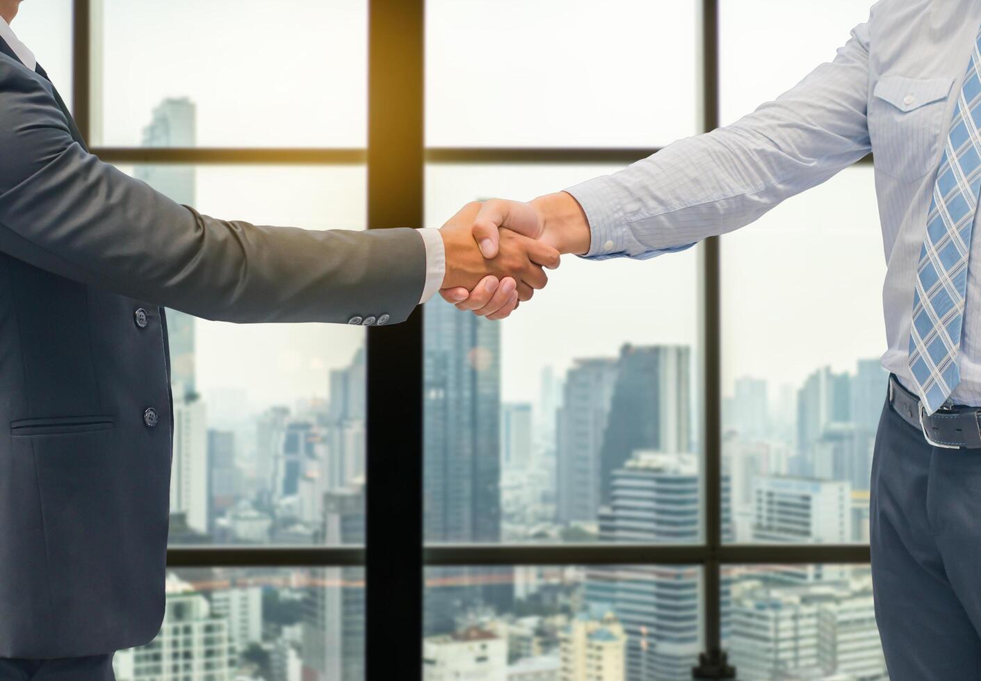 Close up of a business hand shake between two colleagues - greeting, dealing, merger and acquisition concepts on Modern glass building background photo
