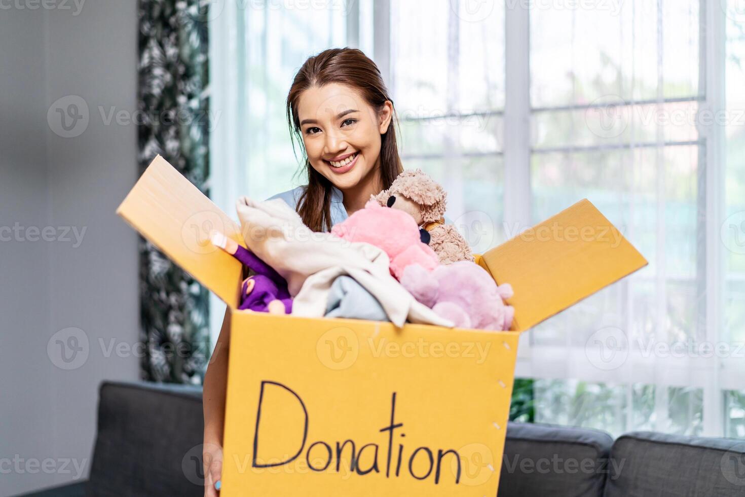 Donation Concept. Happy volunteer asian woman holding a Donate Box with full of toy doll, She working at charity center. photo