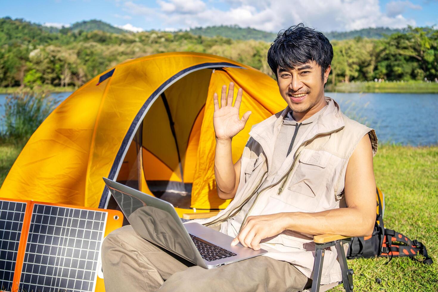 Young travel man relax and enjoy talking calling on on laptop, using laptop computer work remotely anywhere using internet connected to portable solar panel charging photo