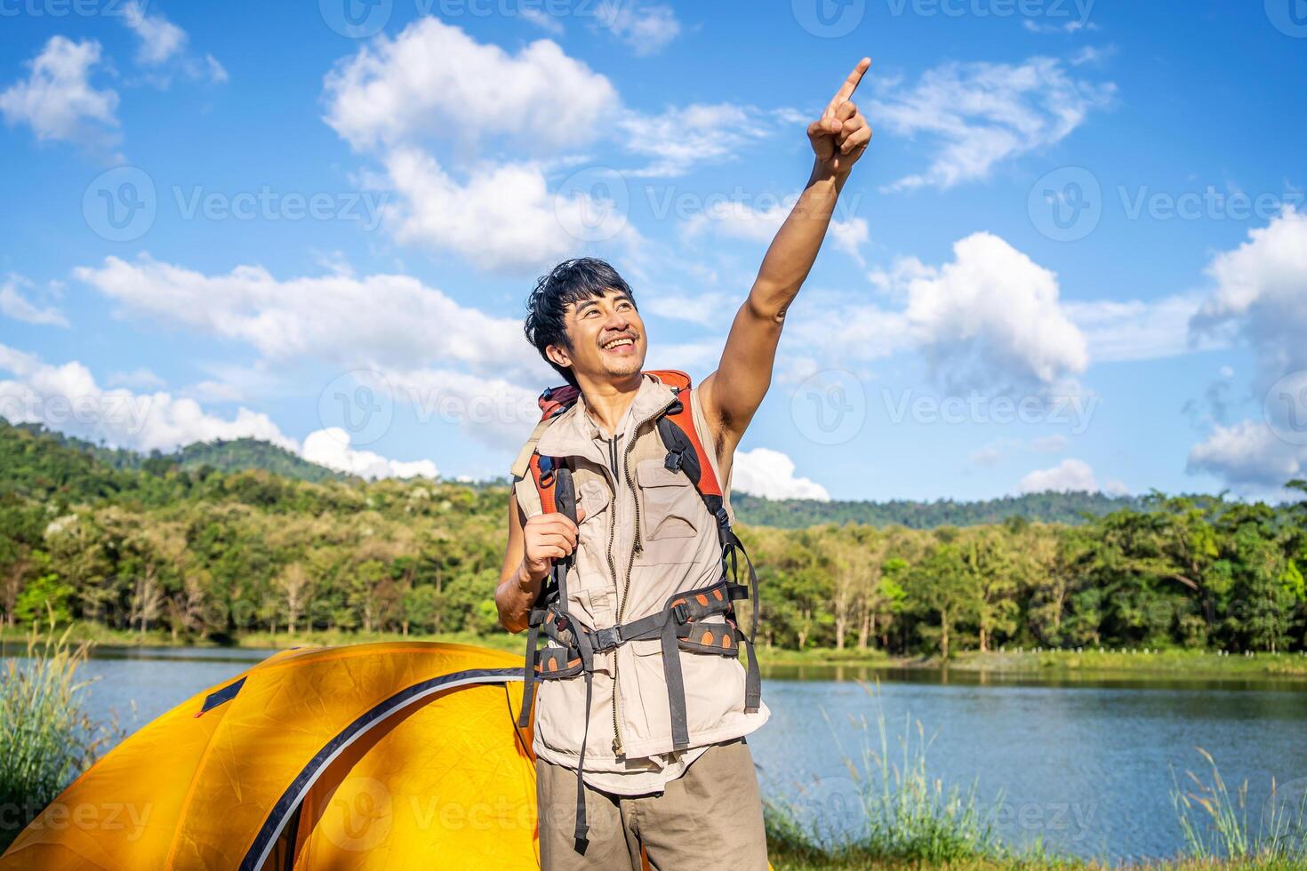 The male traveler left his tent. in order to travel, A man prepares to climb mountains and tighten a backpack, pointing above to the mountain horizon photo
