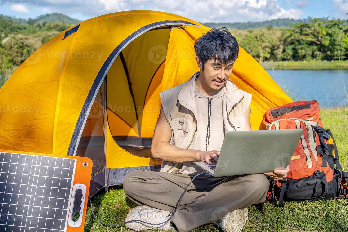 Young travel man relax and enjoy camping . Hand male plug in portable solar panel charging laptop computer by multipurpose cable, Clean energy for using in camping or at home when NO electricity photo
