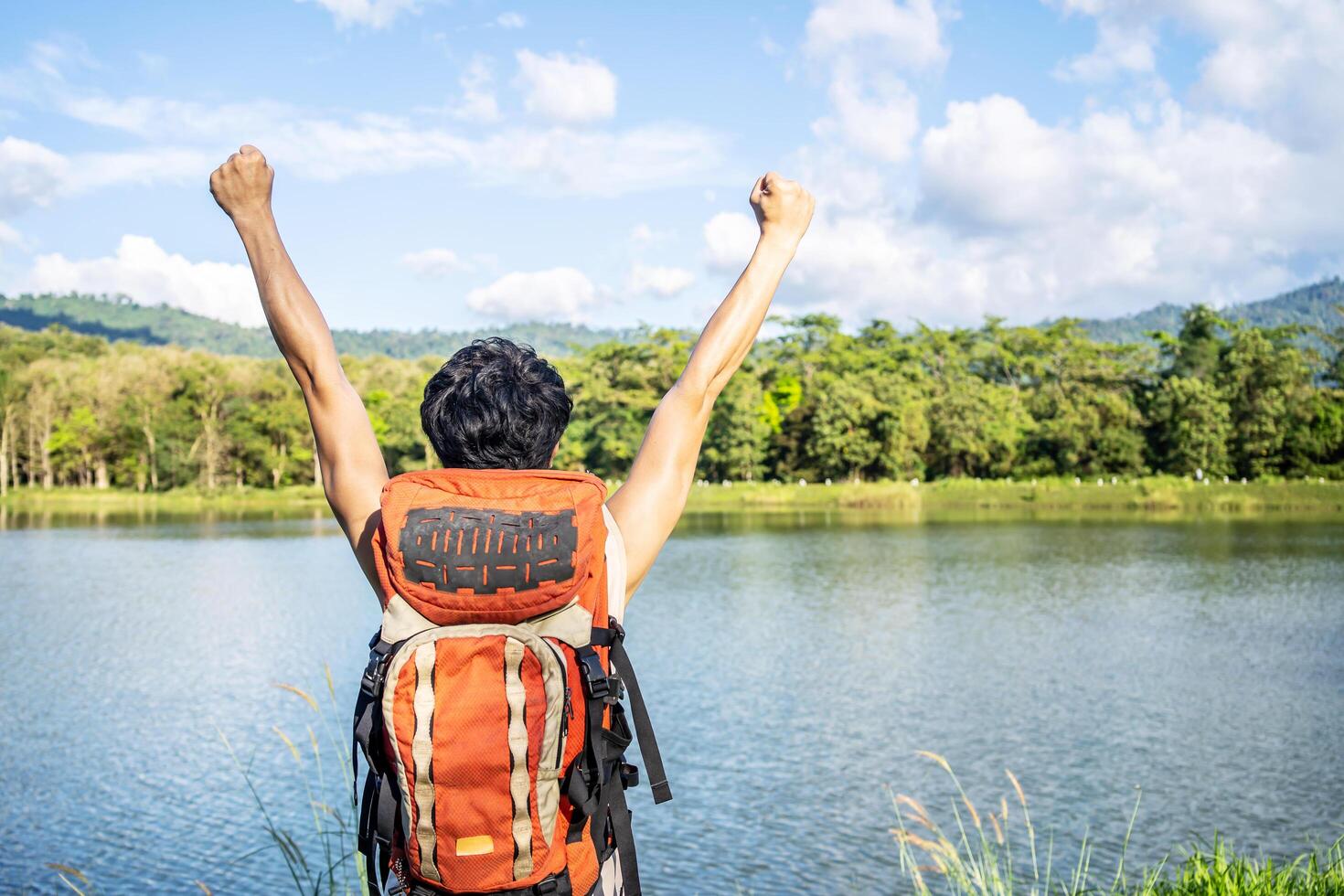 Young asian attractive tourists raise your fist above your head enjoying the nature, Male is happy to come to a picturesque place, spend time on vacation trip in thailand photo