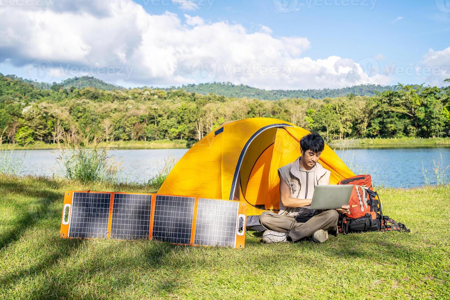 Young travel man relax and enjoy camping . Hand male plug in portable solar panel charging laptop computer by multipurpose cable, Clean energy for using in camping or at home when NO electricity photo