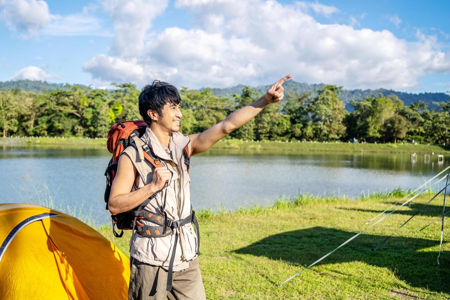 The male traveler left his tent. in order to travel, A man prepares to climb mountains and tighten a backpack, pointing above to the mountain horizon photo
