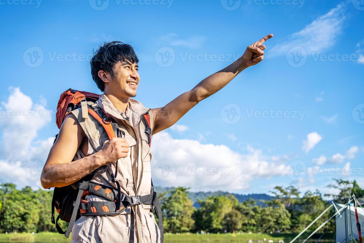 The male traveler left his tent. in order to travel, A man prepares to climb mountains and tighten a backpack, pointing above to the mountain horizon photo