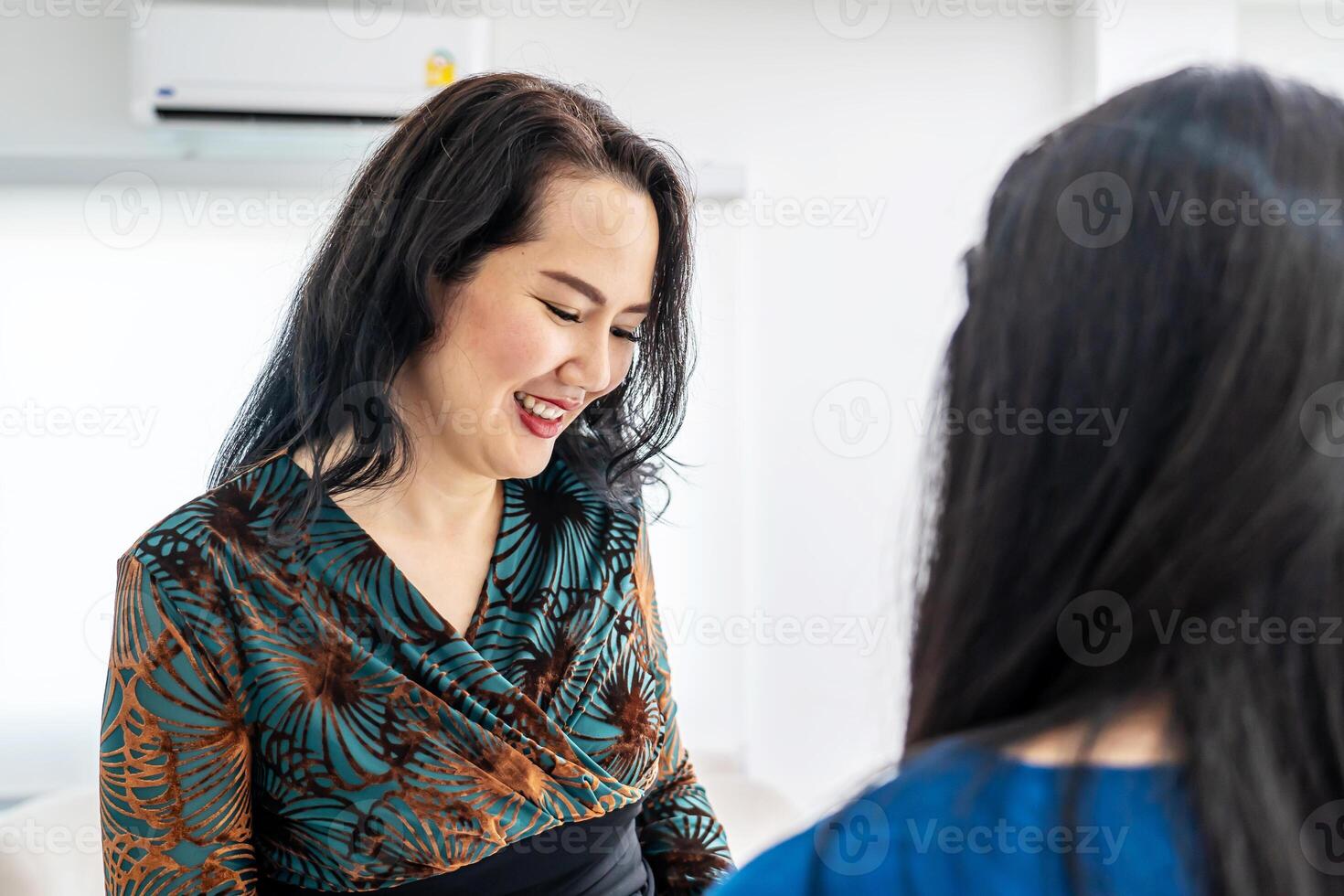 Asian woman comes to reception desk in clinic lobby area and makes appointment with doctor. Female administrator talks with patient at information counter. Medical staff work in medical center photo