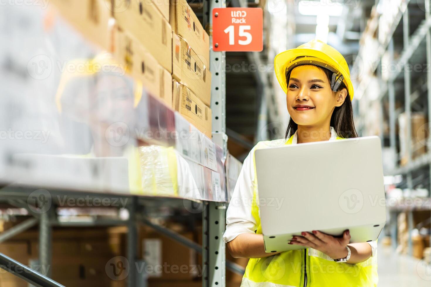 Smiling asian woman warehouse worker doing stocktaking of products management in cardboard box on shelves in warehouse using laptop computer, logistic and business export photo