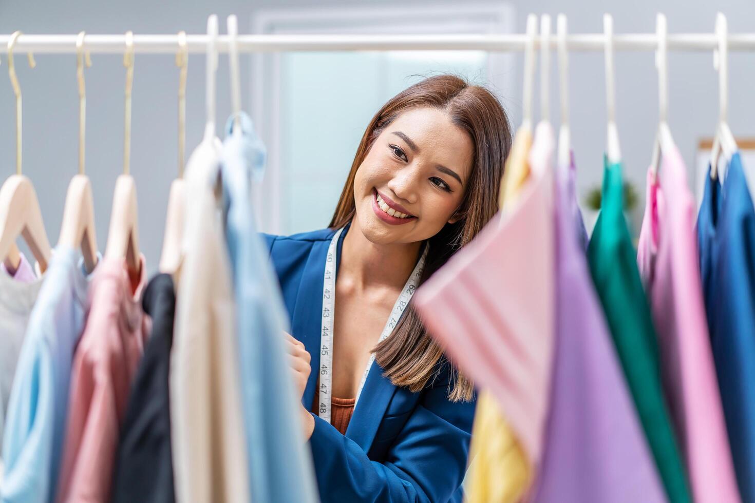 Beautiful woman business owner at fashion store choose clothes in the clothes rail, Fashion designer standing in order to repair, service for customers. Concept Profession Dressmaker designer photo