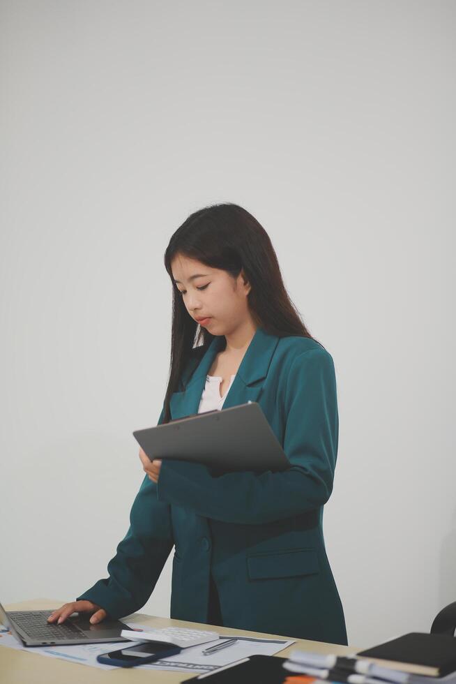 Asian Business woman using calculator and laptop for doing math finance on an office desk, tax, report, accounting, statistics, and analytical research concept photo
