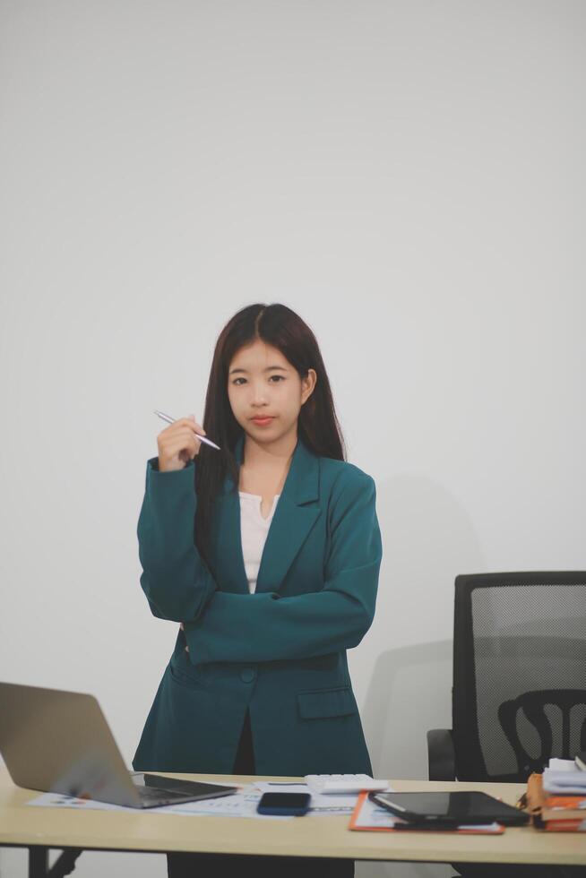 Asian Business woman using calculator and laptop for doing math finance on an office desk, tax, report, accounting, statistics, and analytical research concept photo