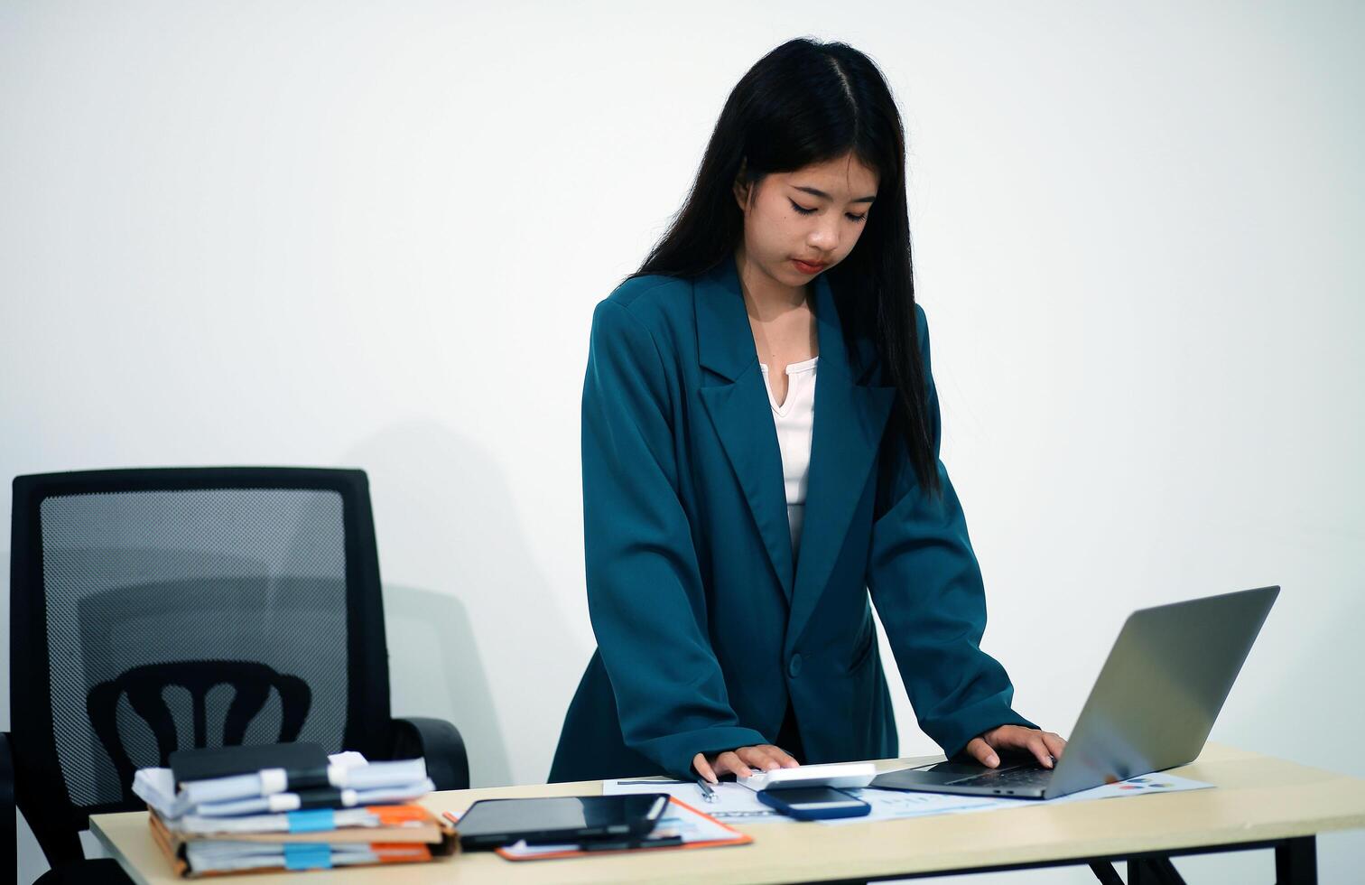 Asian Business woman using calculator and laptop for doing math finance on an office desk, tax, report, accounting, statistics, and analytical research concept photo