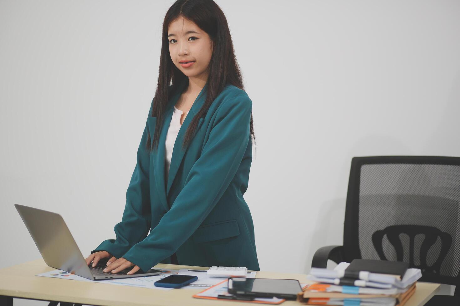 Asian Business woman using calculator and laptop for doing math finance on an office desk, tax, report, accounting, statistics, and analytical research concept photo