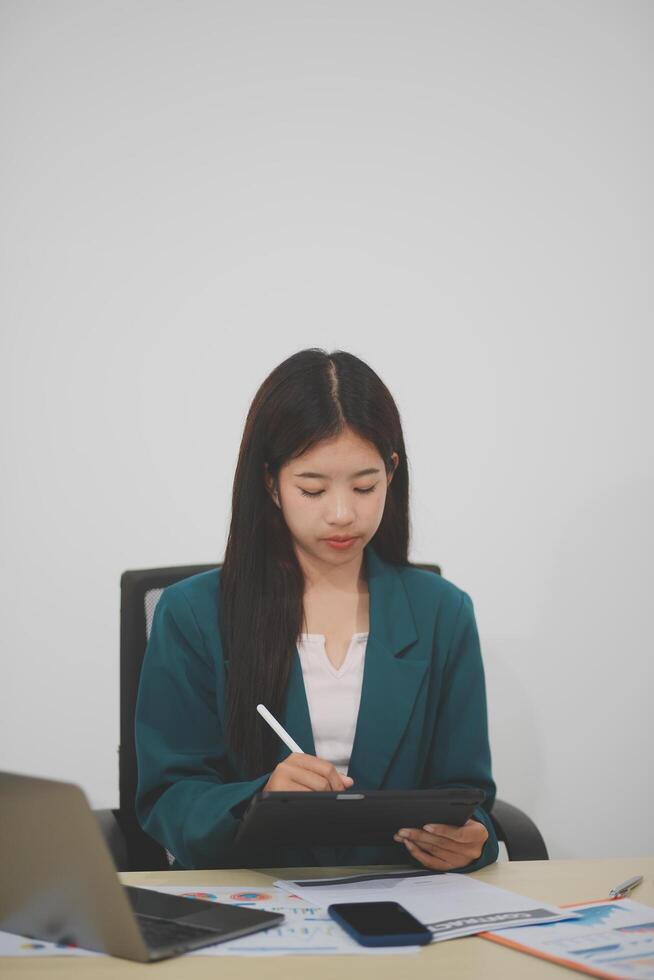 Beautiful Asian businesswoman work using a tablet and a laptop with documents placed at the office. photo