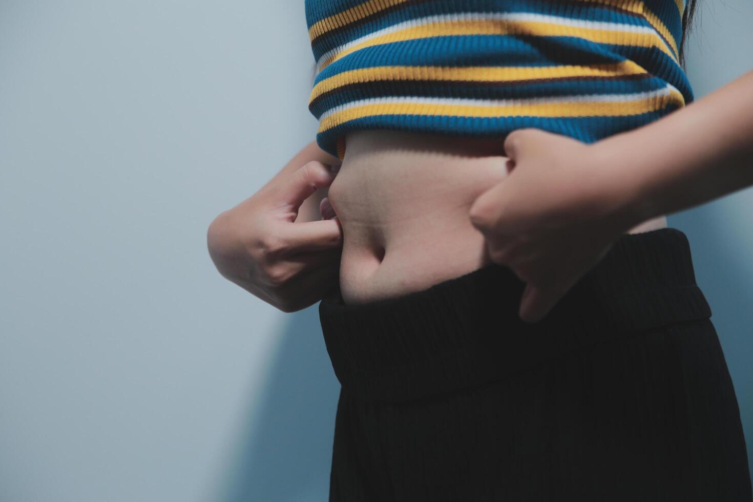 Women body fat belly. Obese woman hand holding excessive belly fat. diet lifestyle concept to reduce belly and shape up healthy stomach muscle. photo